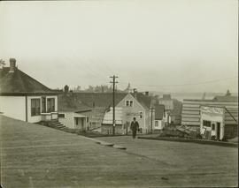 Unidentified man walking up a wood planked street in Prince Rupert, BC